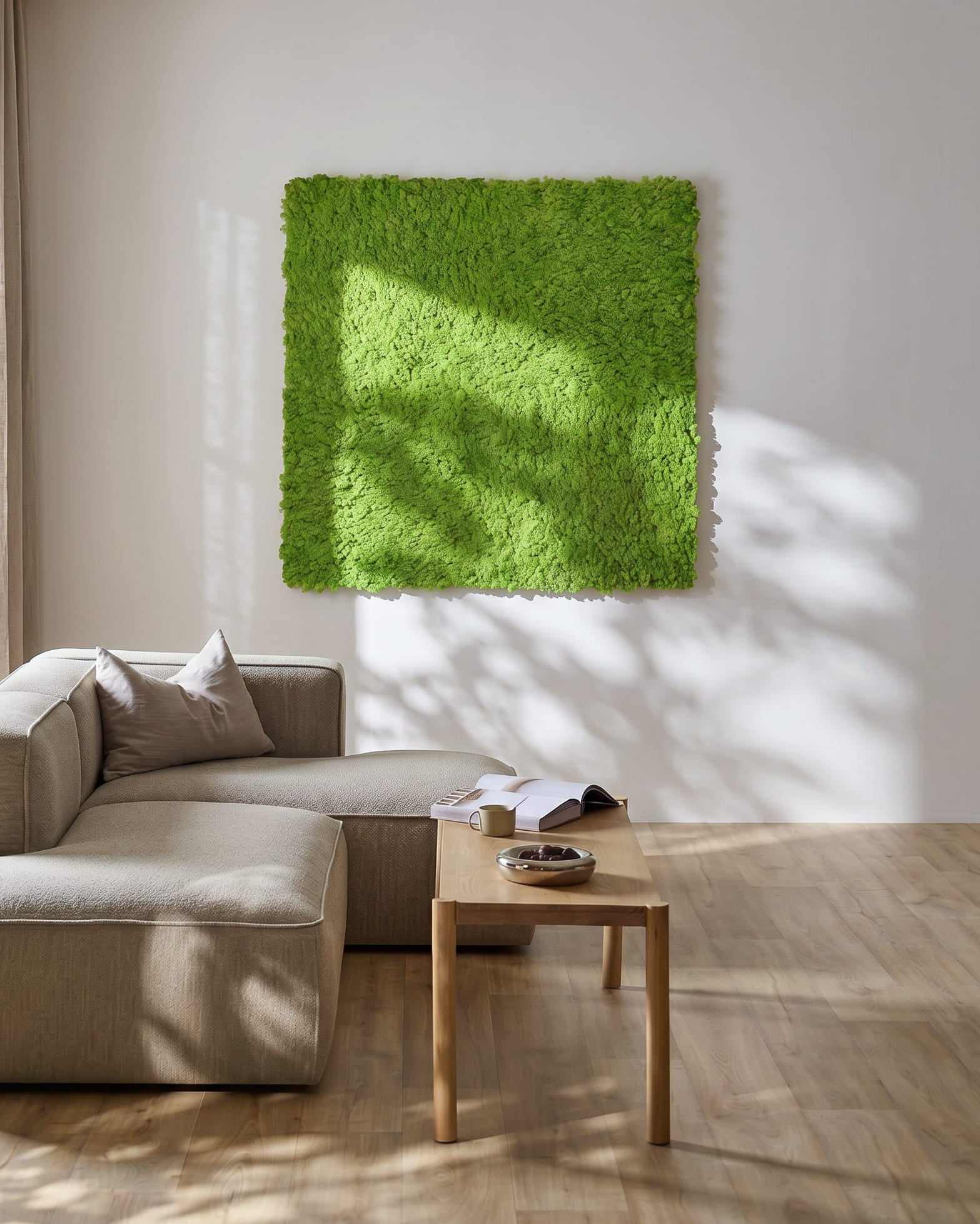 Modern living room with a beige sofa and WoodUpp Akupixel acoustic panel in Moss / Apple Green, 60x60cm, mounted on the wall. Sunlight casts shadows nearby.